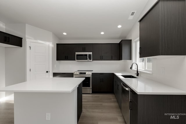 kitchen featuring light wood finished floors, recessed lighting, backsplash, appliances with stainless steel finishes, and a sink