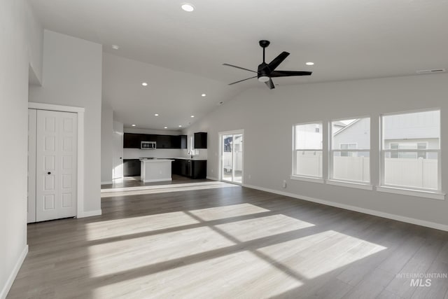 unfurnished living room with lofted ceiling, ceiling fan, recessed lighting, wood finished floors, and baseboards