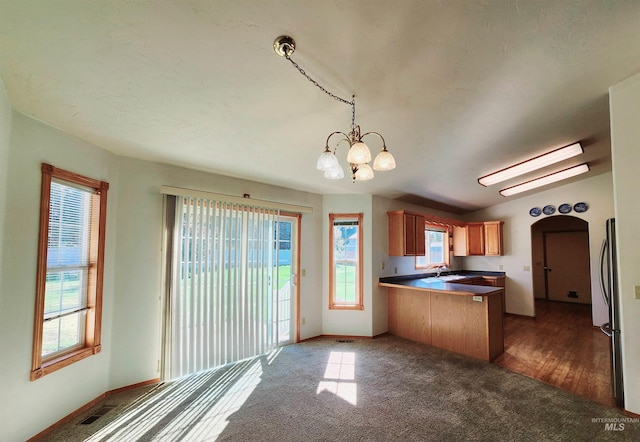 kitchen featuring sink, kitchen peninsula, decorative light fixtures, dark wood-type flooring, and a chandelier