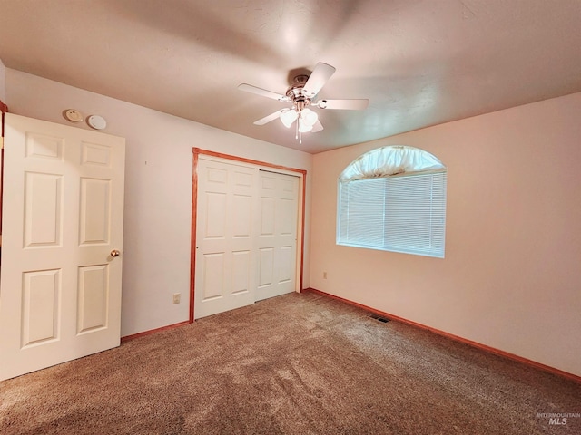 unfurnished bedroom with ceiling fan, carpet floors, and a closet