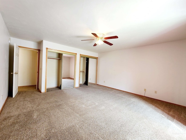 unfurnished bedroom featuring two closets, carpet, and ceiling fan