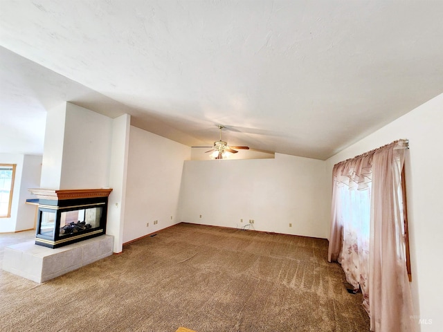 unfurnished living room with ceiling fan, carpet floors, a multi sided fireplace, and vaulted ceiling