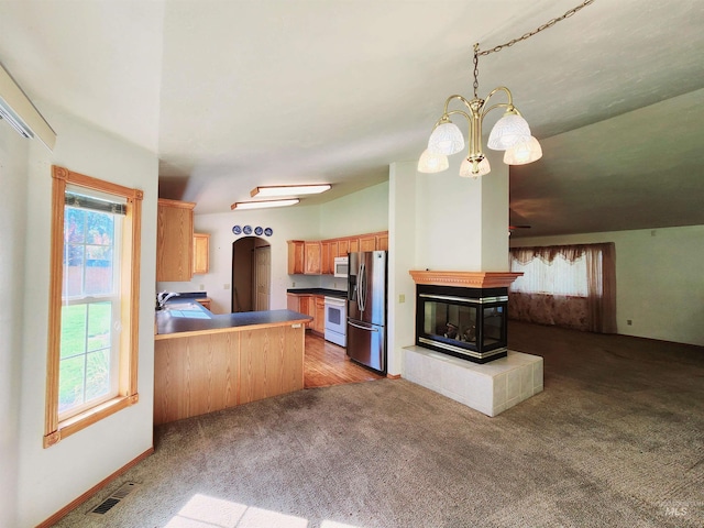 kitchen with kitchen peninsula, white appliances, decorative light fixtures, a chandelier, and a fireplace