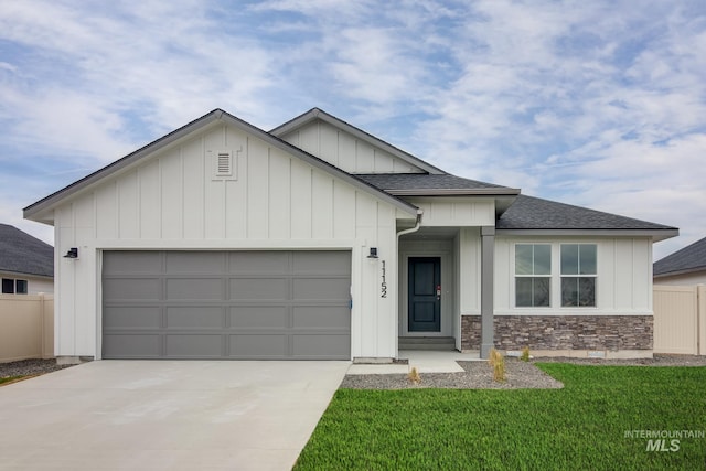 view of front of house with a garage, board and batten siding, driveway, and fence