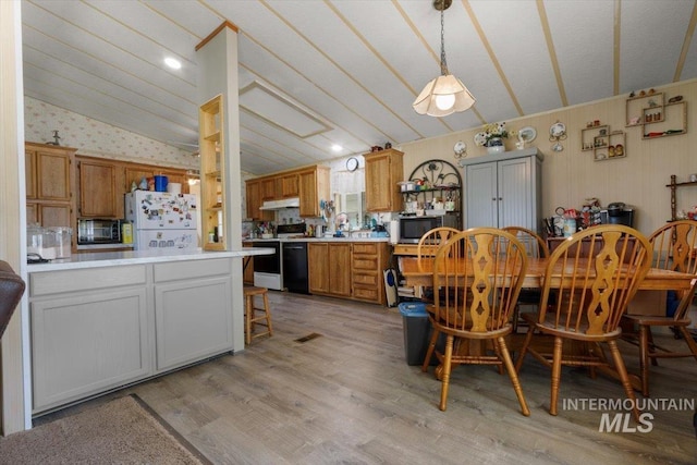dining room featuring wallpapered walls, light wood finished floors, and lofted ceiling