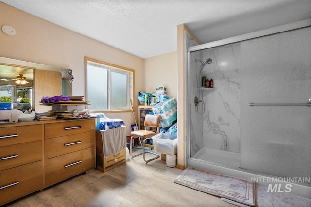 full bathroom featuring a marble finish shower, a ceiling fan, vanity, and wood finished floors