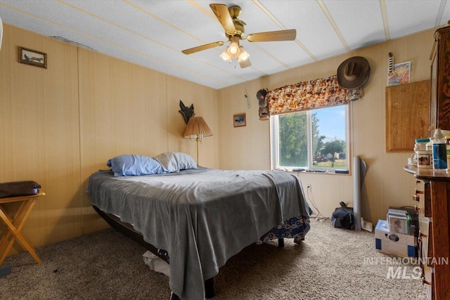 bedroom featuring wooden walls, a ceiling fan, and carpet flooring