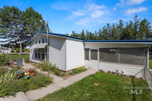 view of property exterior featuring a sunroom and a yard