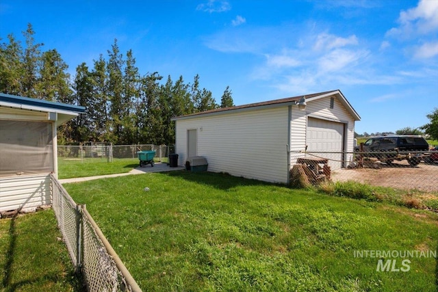 view of yard featuring fence, an outbuilding, and a detached garage