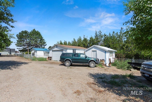 manufactured / mobile home featuring an outbuilding, a detached garage, fence, and driveway