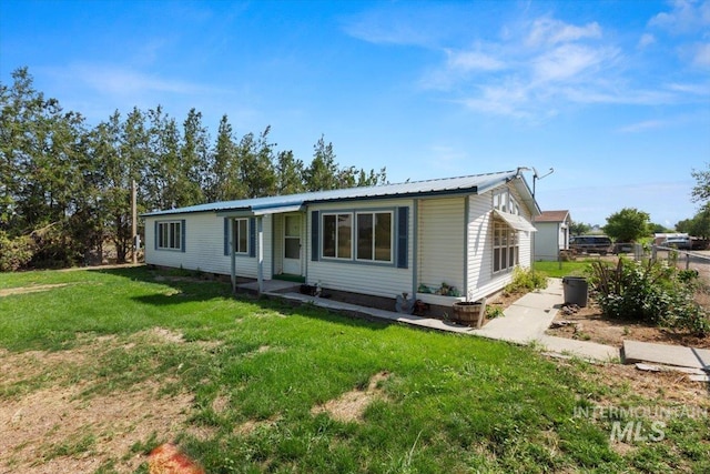 view of front of property with a front yard, fence, and metal roof