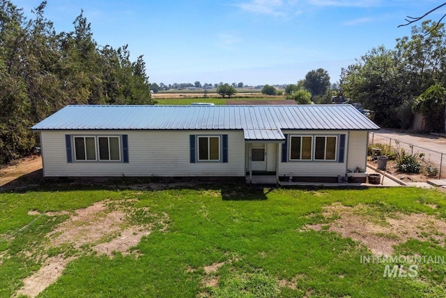 back of property with metal roof, fence, and a lawn