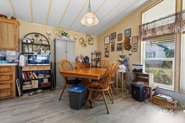 dining space with light wood-style flooring and vaulted ceiling