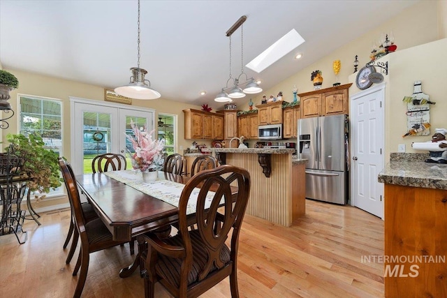 dining space featuring light hardwood / wood-style floors and vaulted ceiling with skylight