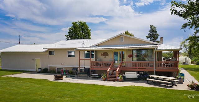 back of property with metal roof, a patio, stairway, and a lawn