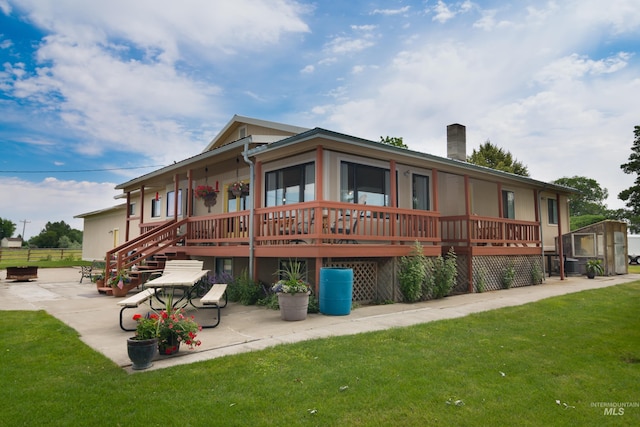 back of house featuring an outbuilding, a yard, a chimney, and a patio area