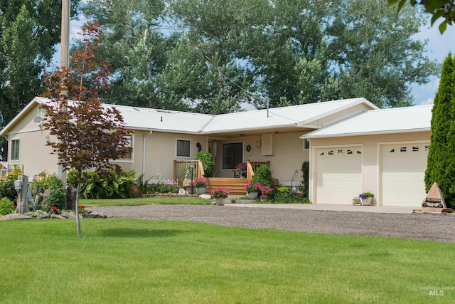 ranch-style home featuring a garage, driveway, metal roof, a front yard, and stucco siding