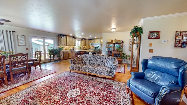 living area with crown molding and light wood-style flooring