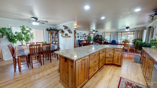 kitchen with light wood finished floors, a kitchen island, brown cabinets, and crown molding