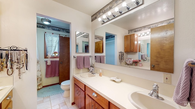 full bath featuring double vanity, a sink, and toilet