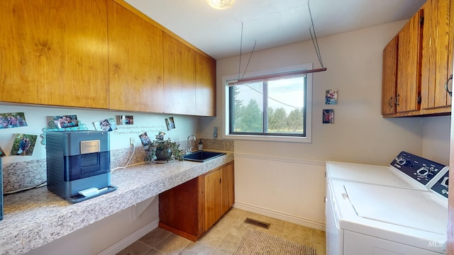 clothes washing area featuring cabinet space, visible vents, wainscoting, independent washer and dryer, and a sink