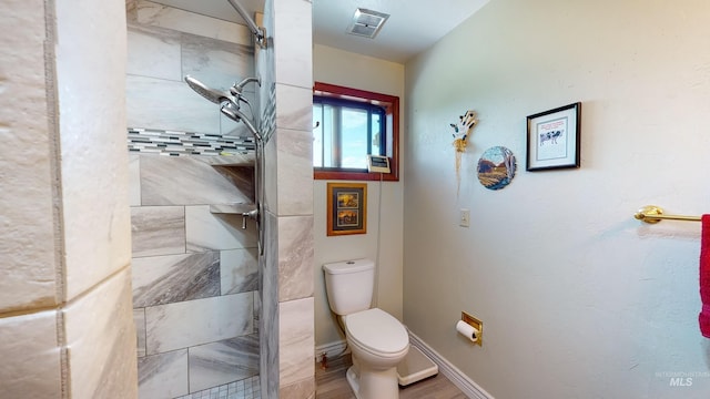 full bath with baseboards, visible vents, toilet, and tiled shower