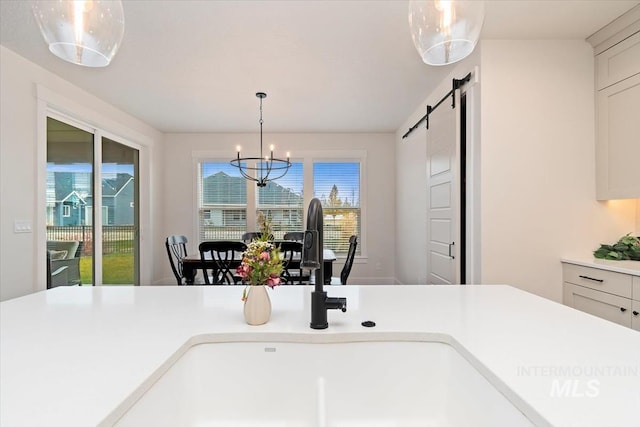 kitchen with a notable chandelier, plenty of natural light, a barn door, and sink