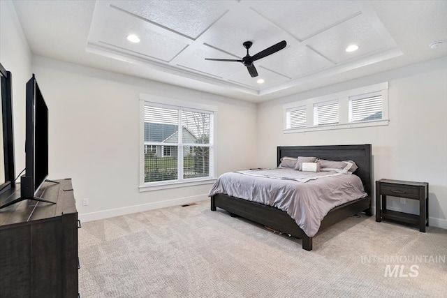 bedroom with ceiling fan, light colored carpet, and a tray ceiling