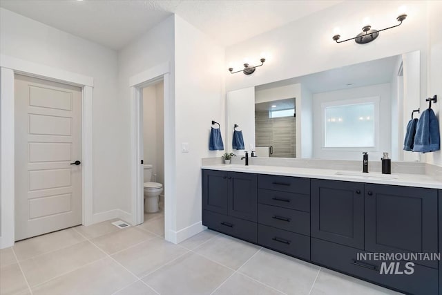 bathroom with walk in shower, tile patterned flooring, vanity, and toilet