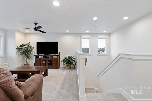 carpeted living room with ceiling fan and a textured ceiling