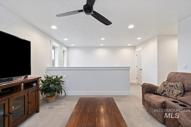 living room featuring light carpet, ceiling fan, and a textured ceiling