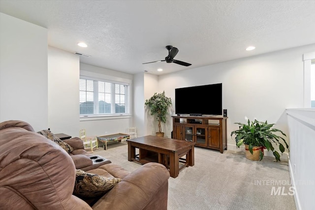 carpeted living room featuring ceiling fan and a textured ceiling