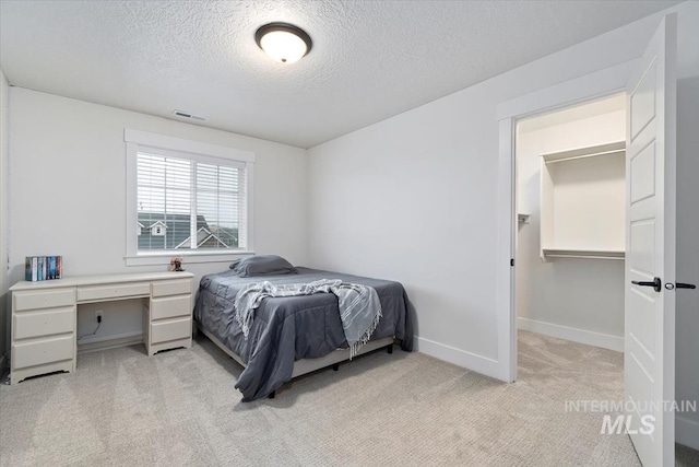 carpeted bedroom with a textured ceiling and a spacious closet