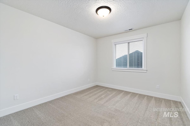 carpeted spare room with a textured ceiling