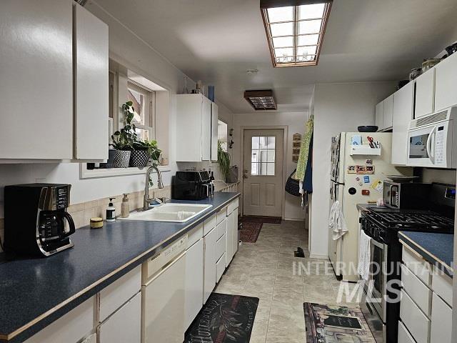 kitchen with white cabinetry, sink, light tile patterned floors, and white appliances