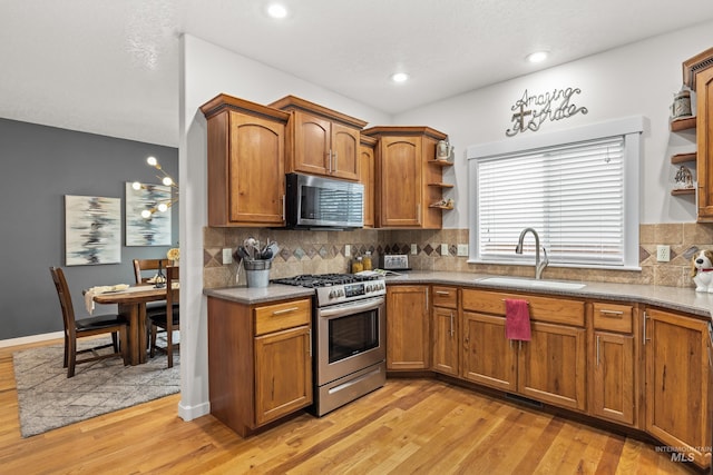 kitchen with appliances with stainless steel finishes, light hardwood / wood-style floors, sink, and backsplash