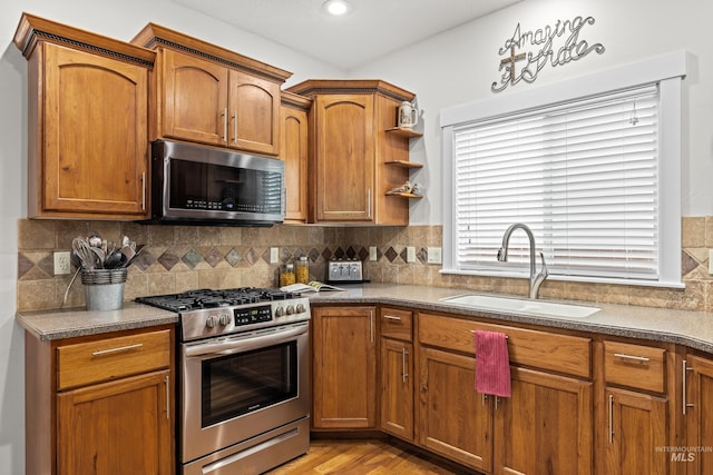 kitchen featuring sink, decorative backsplash, light hardwood / wood-style flooring, and appliances with stainless steel finishes