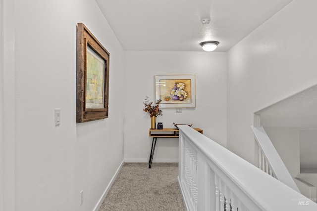 hall featuring light carpet and a textured ceiling