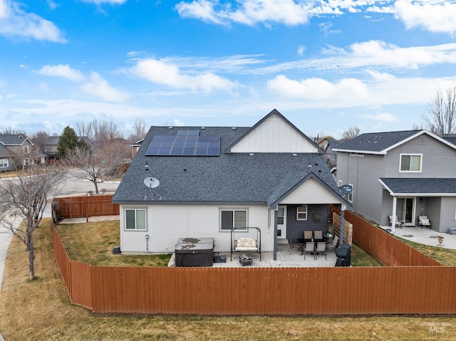 rear view of house featuring a lawn, a patio, and solar panels