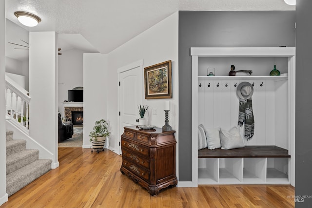 mudroom with hardwood / wood-style floors, a textured ceiling, and a fireplace