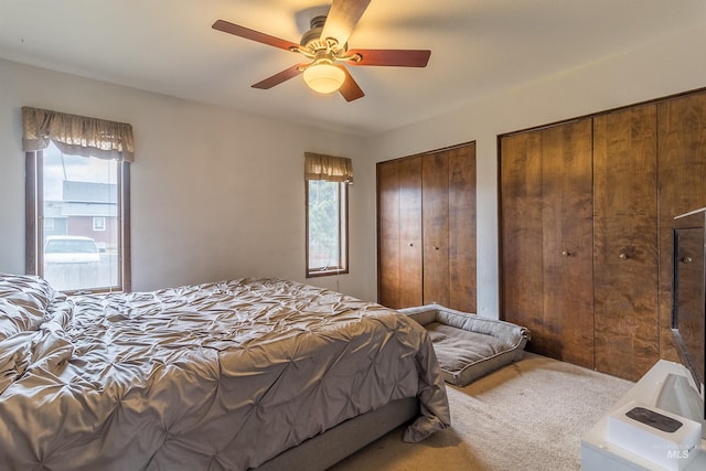 carpeted bedroom featuring two closets and ceiling fan