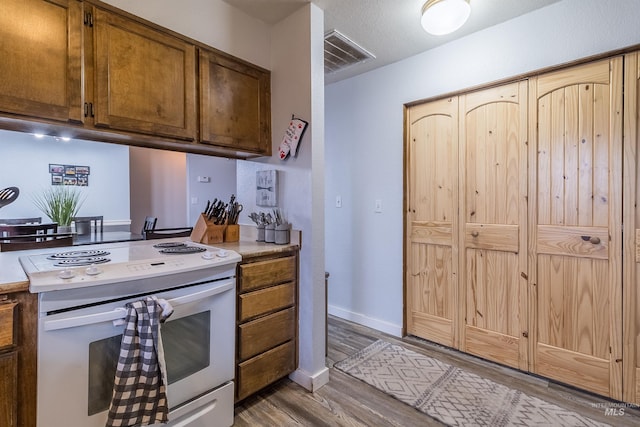 kitchen with visible vents, baseboards, light countertops, light wood-type flooring, and white range with electric stovetop