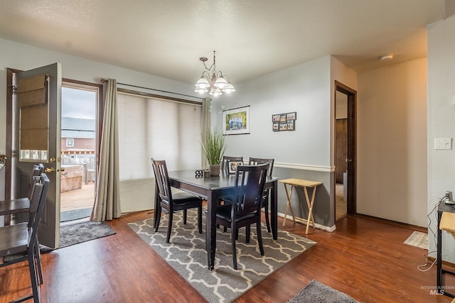 dining room featuring dark wood-style floors, baseboards, and an inviting chandelier