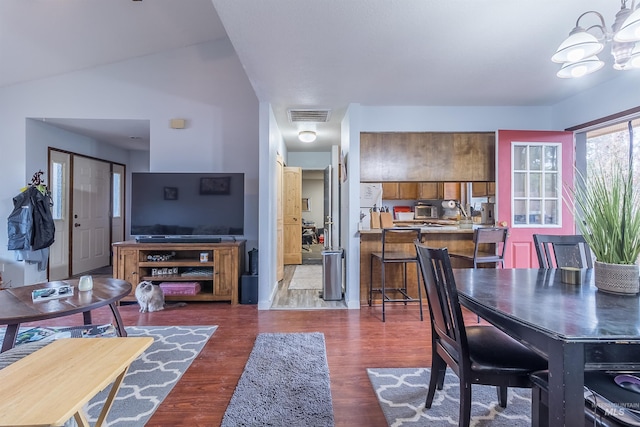 dining area featuring visible vents, lofted ceiling, wood finished floors, and a chandelier