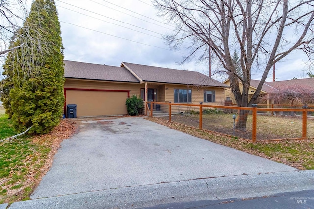 ranch-style home featuring a fenced front yard, driveway, an attached garage, and roof with shingles