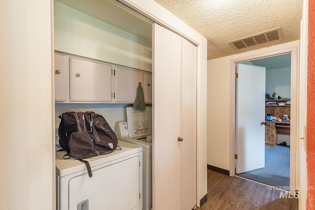 laundry area featuring cabinet space, washing machine and clothes dryer, visible vents, a textured ceiling, and dark wood finished floors