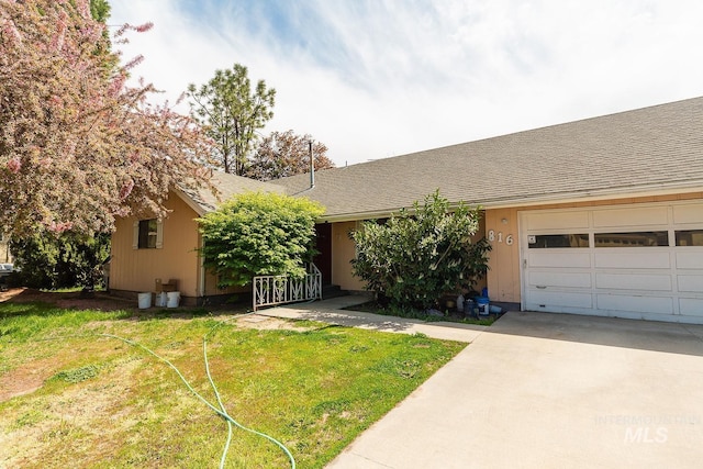 ranch-style house featuring roof with shingles, driveway, and a front yard