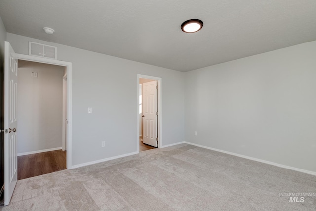 unfurnished bedroom with light colored carpet and connected bathroom