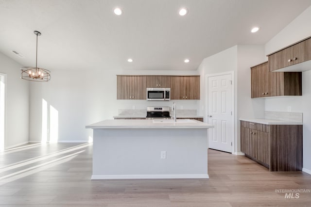 kitchen with light hardwood / wood-style flooring, hanging light fixtures, appliances with stainless steel finishes, sink, and plenty of natural light