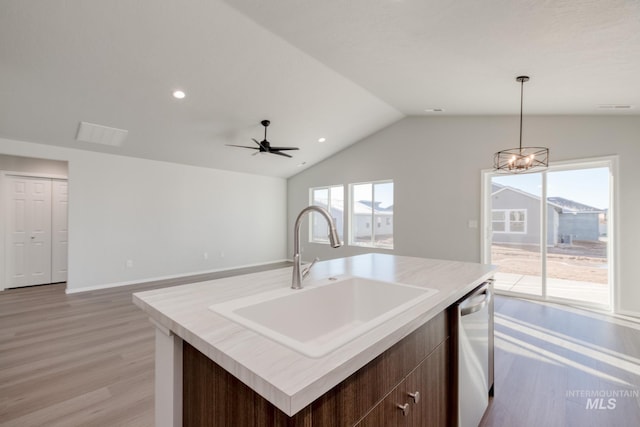 kitchen with pendant lighting, dishwasher, light hardwood / wood-style floors, sink, and a center island with sink